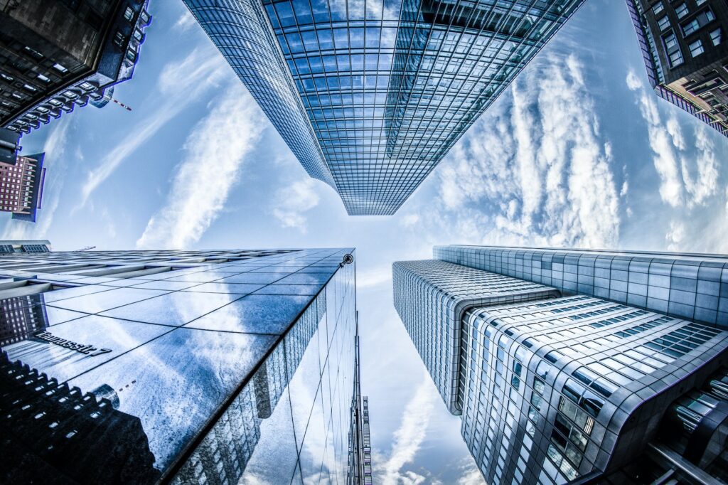 low angle photo of four high rise curtain wall buildings under white clouds and blue sky